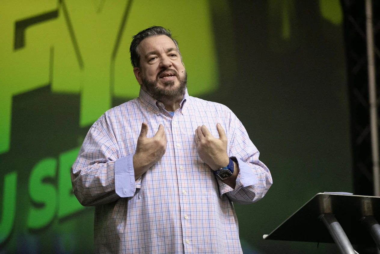 Lon Dean teaching on stage beside a lectern.